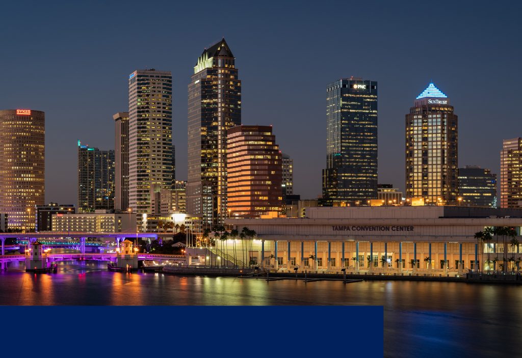 A city skyline with buildings lit up at night.